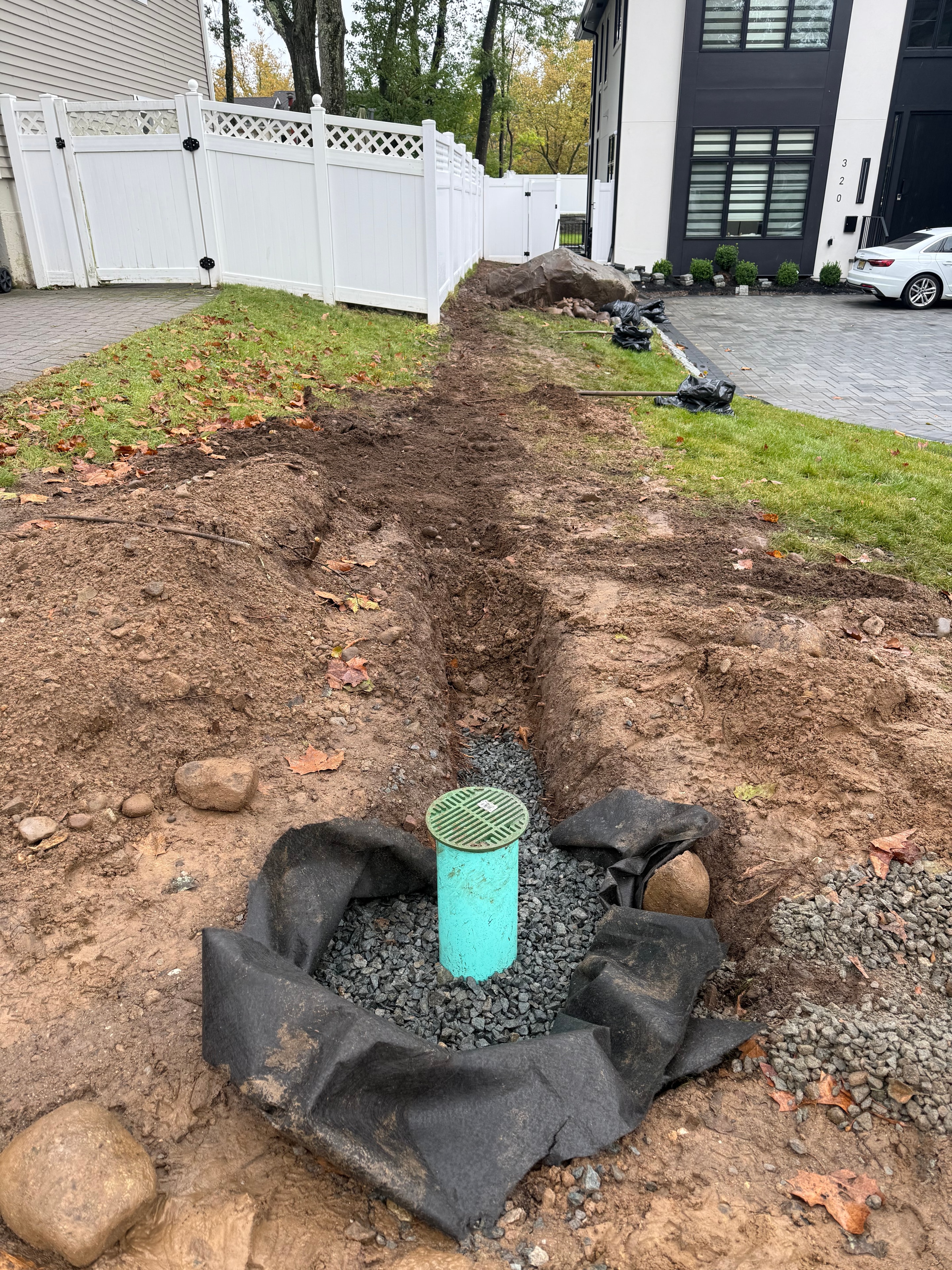 Drainage outlet pipe, gravel aggregate, and filter fabric installed in excavated trench — Paramus, NJ, work in progress